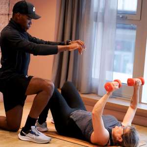 Un coach sportif "ElieB Coaching" guide une femme lors d'une séance de musculation à domicile à Angers.