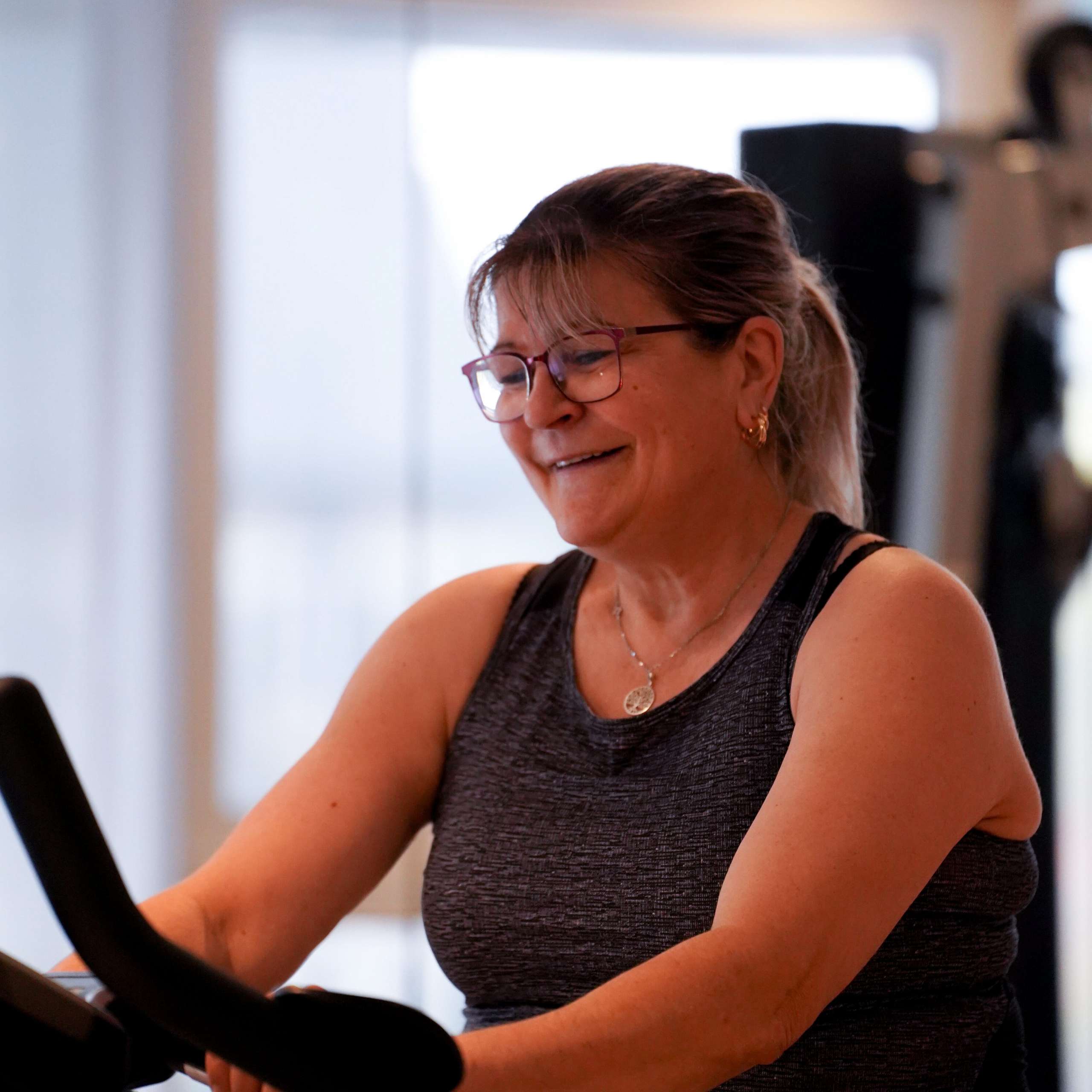 Une cliente souriante et motivée après une séance de coaching sportif.