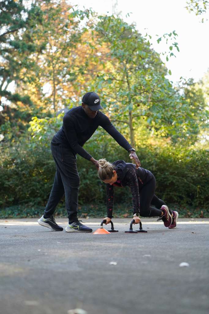 Élie B Coaching en train de coaché une cliente sur un mouvement de gainage dans un parc à Angers